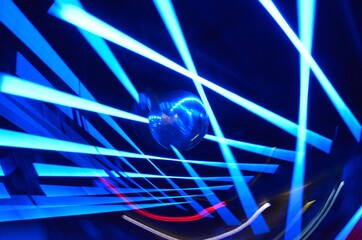 Long exposure photo of a mirroball, color LED and Neon lights with camera motion and dark background