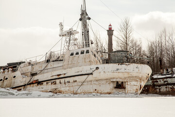 Fototapeta premium Abandoned white ship frozen in ice near lighthouse