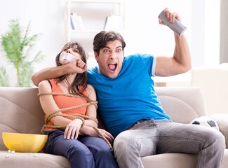 Man tying up his wife to watch sports football