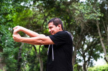 young peruvian man warming up by stretching arms before exercise