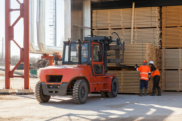 workers load boards with an industrial loader at a sawmill