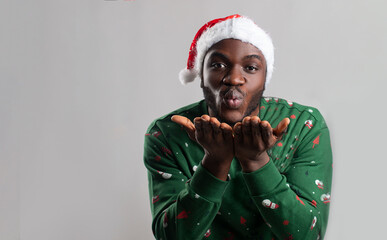 Handsome african american wearing santa clause hat blowing to the camera joyfully. African santa...