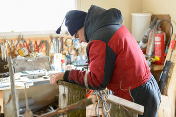 Mature handsome man making bird house indoors