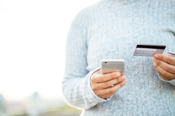 A woman using a credit card to pay for goods online with a mobile phone