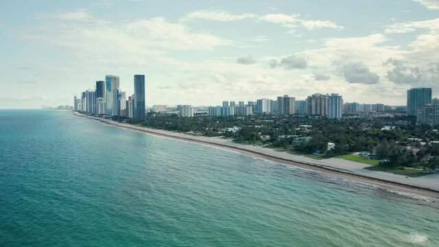 4K aerial view of clean and warm teal waters of Atlantic ocean. Residential front line buildings with beautiful sea view. South Beach nature at sunset, Florida, USA. Background for travel business