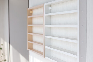 Fototapeta na wymiar White Wooden Shelf on a Wall in Light Room.