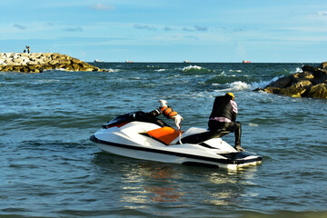 
A dog wearing a life jacket Driving a scooter on the seashore