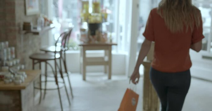 Young adult Female purchasing items using smart phone, wireless technology and walking away with shopping bag