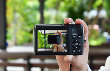 Compact digital camera Black in hand and photo.