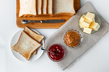 Toast bread with butter, homemade strawberry jam and peanut butter on a table