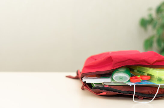 Back to school. Education and social distance concept. Protective medical mask, antibacterial hand cleaning gel (alcohol gel), school supplies lie in a backpack on a light background. copy space