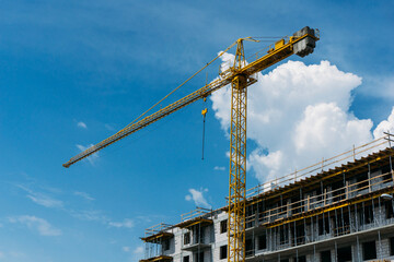Empty copy space crane background. Yellow paint heavy machinery equipment isolated on blue cloudy sky. Construction site view. Industrial building process. Block of flats in progress.