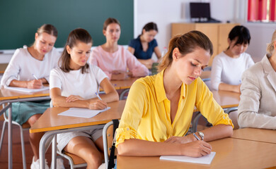 Group of focused female students writing notes in auditorium