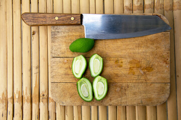 green mango fruits and knife on Butcher on bamboo background, top view