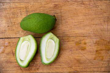 green mango fruits on the wooden background, top view