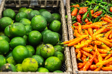 Basket with red and green chilli pepper and basket with green limes in the shop