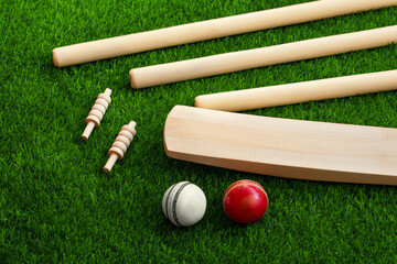 cricket set bat ball stumps and bails on green grass pitch background