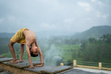 A young indian cute kid doing yoga in the mountains,wearing a dhoti