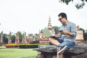 Tourist working and using laptop at Sukhothai historical park, Thailand. Vacation and holiday concept