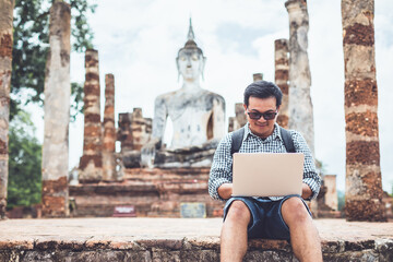 Tourist working and using laptop at Sukhothai historical park, Thailand. Vacation and holiday...