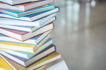 Book stack on the table in the library room and blurred space of bookshelf background