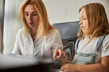 Charming blonde Caucasian female in white shirt sitting at the work desk