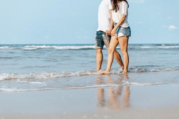 Romantic couple holding hands and walking on beach. Man and woman in love.