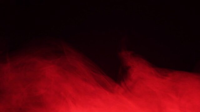 Red smoke spreads like fog. Texture of cigarette white smoke on a black background. Slow motion.