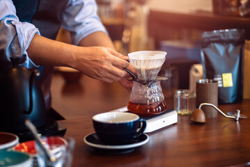 Fototapeta na wymiar Barista measuring coffee drip with glass mug