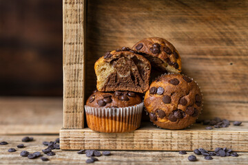 Soft and moist chocolate banana muffins with dark chocolate drops in wooden box, rustic table....
