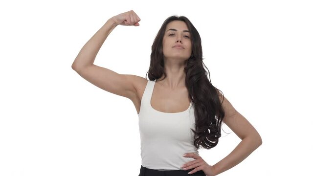 Portrait of young self-confident Caucasian woman showing muscles looking at camera. Isolated on white background