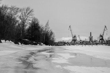 Winter industrial landscape with  factory cranes in frozen port