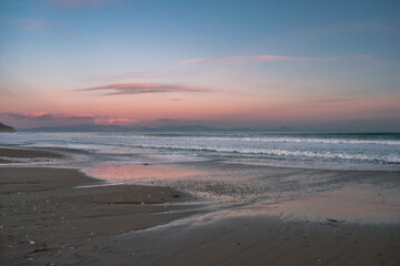 Sea with waves, sea foam and sandy beach at dusk