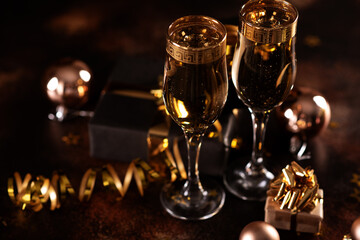 Christmas champagne, gas bubbles, confetti and blurry lights on a dark background.
