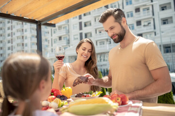 Young cute family having dinner outside and looking contented