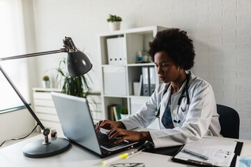 Woman doctor with stethoscope looking at medical papers at her office working hard
