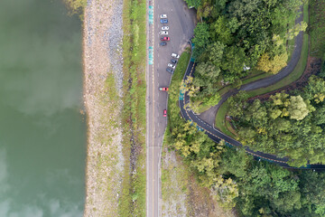 Aerial view top down photo from flying drone of asphalt road with cars and bicycle lane curve road around the dam.