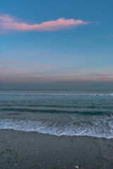 Sea with waves, sea foam and sandy beach at dusk