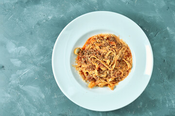 Pasta (tagliatelli) bolognese with red sauce and minced meat in a white plate