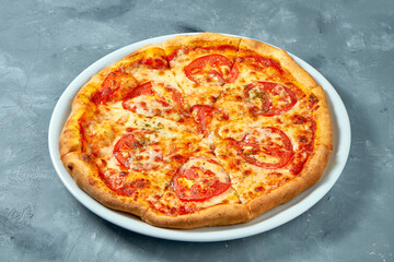 Classic italian pizza margarita with tomatoes and cheese in a white plate on a concrete background