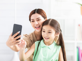 happy mother and daughter taking selfie by  smart phone