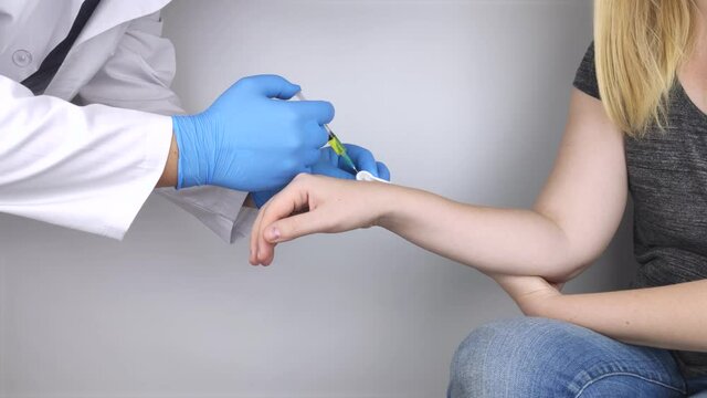 An orthopedic surgeon gives an injection in the wrist. Treatment of osteoarthritis with hormonal drugs or drugs based on hyaluronic acid. Help with diseases that damage the cartilage of the joint