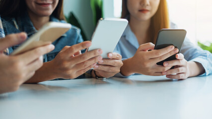 Group of young people using and looking at mobile phone while sitting together