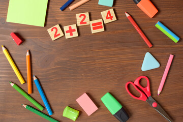 .Stationery on a wooden background for children to school, two plus two equals four.