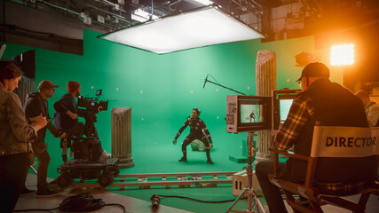 In the Big Film Studio Professional Crew Shooting Blockbuster Movie. Director Commands Cameraman to Start shooting Green Screen CGI Scene with Actor Wearing Motion Capture Suit and Head Rig - obrazy, fototapety, plakaty