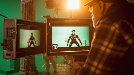 Director Looks at Displays Directs Green Screen CGI Scene with Actor Wearing Motion Tracking Suit...