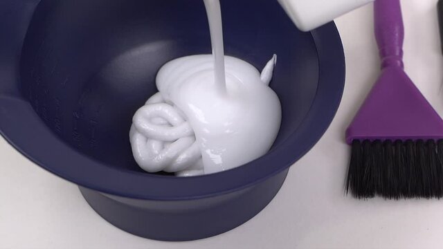 Beauty salon. The hairdresser prepares the composition for hair coloring. Close-up of a mixture of professional hairdressing paints.