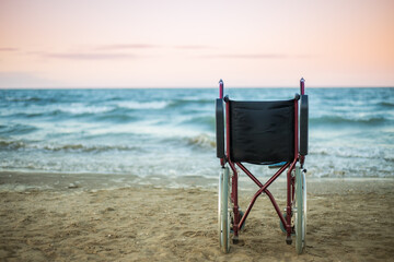 One wheelchair stands by the sea at sunset.Copy space