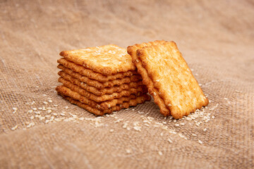 A cracker or cookie with sesame seeds on a burlap or jute cloth