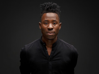 portrait of an African young man in a black shirt on a black background